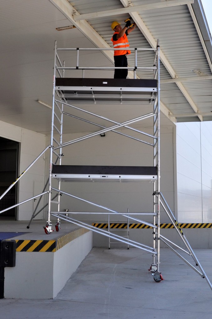 Κινητός αλουμινένιος πύργος σκαλωσιάς για εργασία ύψους σε χώρο logistics.