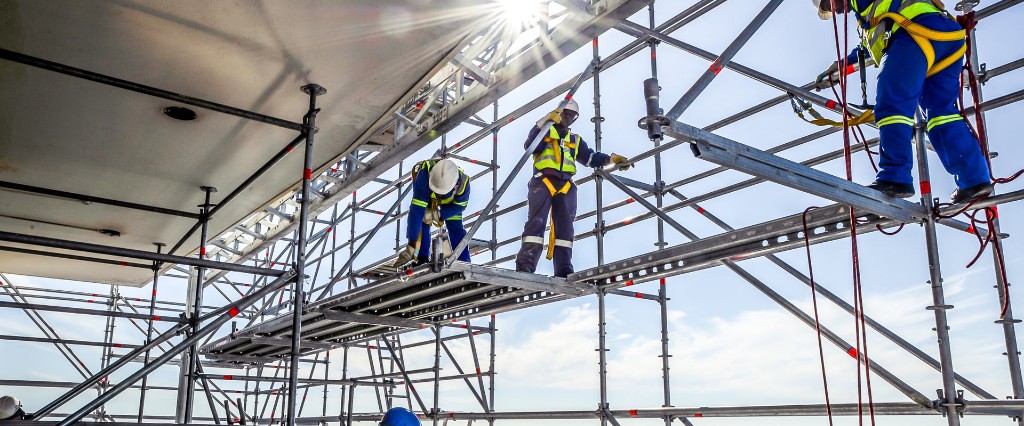 Ομάδα σε σύνθετη σκαλωσιά με φυσικό φωτισμό και εξοπλισμό ασφαλείας.
